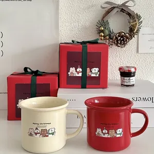 Close-up of festive ceramic mugs in beige and red with cute bear illustrations in a gift box