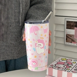 Hand holding a pink stainless steel dog tumbler with cute cartoon patterns and straw