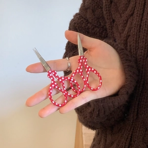Close-up of mini red polka dot craft scissors with a clear safety protective cap