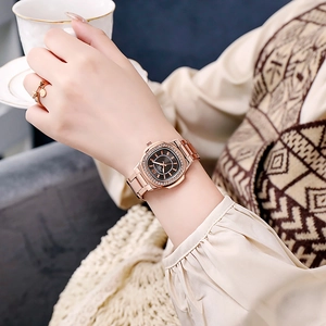 Close-up of a rose gold quartz watch with a diamond bezel and brown sunray dial on wrist