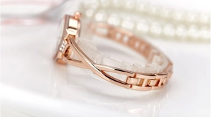 Vista macro laterale dell'orologio a bracciale in oro rosa con design incrociato e strass