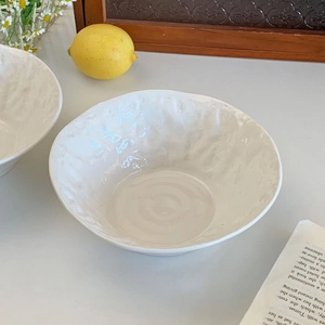 Detail of white ceramic bowl with unique hammer texture finish and irregular wavy rim