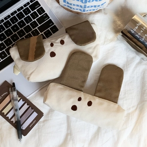 Detail view of cute canvas puppy pencil cases on a desk with aesthetic props