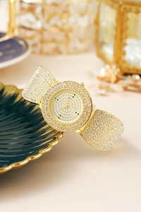 Close-up of luxury women's gold quartz watch with rhinestones on a decorative tray