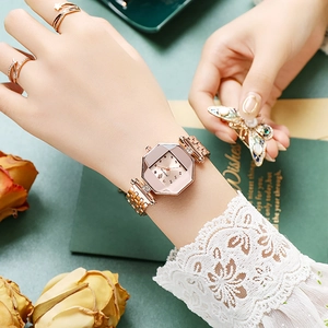 Close-up of rose gold octagonal quartz watch worn with elegant jewelry and lace cuff