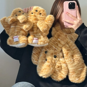 Detail of plush orange tabby cat pattern winter gloves with fluffy texture and cute pom-poms