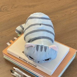 Dettaglio dell'astuccio a forma di gatto grigio in peluche con texture morbida su tavolo