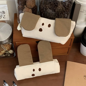 Detailed view of cream canvas puppy pencil cases with cute embroidered faces and fabric ears