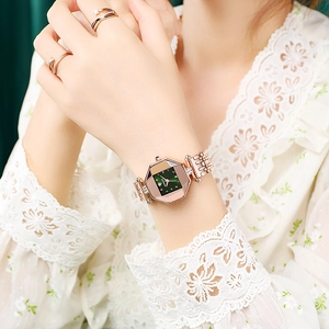 Elegant rose gold watch with emerald green dial and faceted case on female wrist