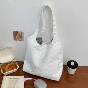 Detail of white star print tote bag with bow tie closure and striped lining