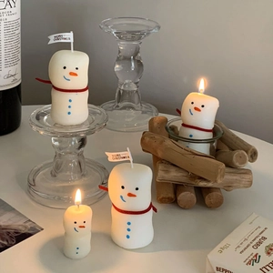 Macro detail of three snowman scented candles with red ribbon and Merry Christmas flags