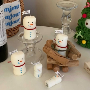 Macro detail of snowman scented candles with festive scarves and Merry Christmas flags