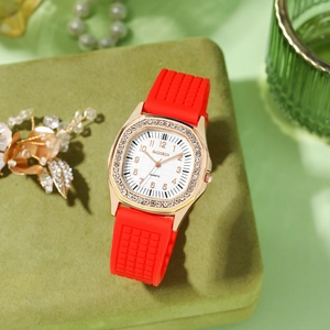 Detail of red silicone strap and sparkling rhinestone bezel on square gold quartz watch