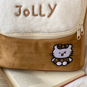 Detailed close-up of plush cosmetic bag with JOLLY embroidery and faux fur texture