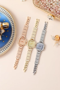 Detail shot of three elegant square rhinestone-encrusted quartz watches in gold and silver.