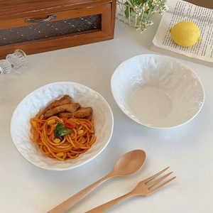 Top-down view of a white ceramic bowl with rock texture and wavy rim for salads