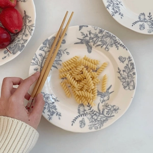 Top view of French vintage ceramic plate with blue bird pattern and wooden chopsticks