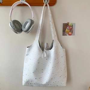 Detail of white star-print tote bag with silver star patterns and striped lining