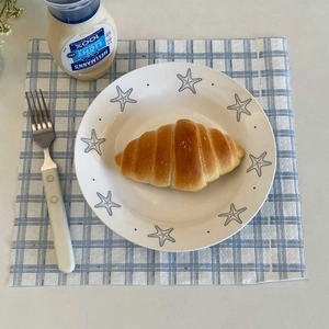 Detail of a ceramic starfishes plate with a golden croissant on a checkered napkin