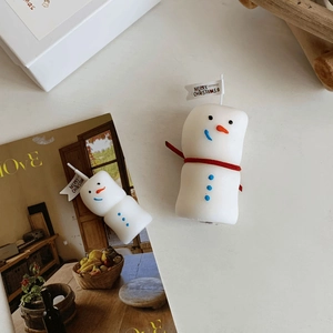 Detail of a snowman scented candle with a red ribbon scarf and Merry Christmas flag