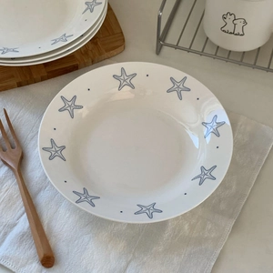 Detailed view of ceramic round plate with blue starfish motifs and hand-painted dots
