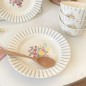 Detail of vintage French floral ceramic bowl with blue radial stripes and floral center