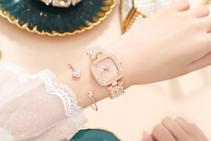 Elegant rose gold square women's watch with rhinestones on a wrist with lace detail