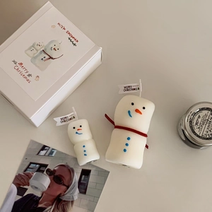 Detail of white snowman scented candle set with red scarves in festive gift box