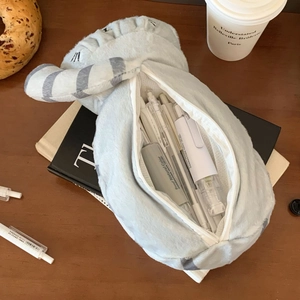 Dettaglio dell'astuccio a forma di gatto grigio in peluche con cancelleria su tavolo