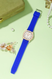 Macro detail of square rose gold watch case with sparkling diamonds and blue silicone strap