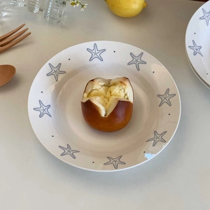 Close-up of a white ceramic plate with blue starfish patterns holding a pastry