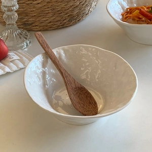 Macro view of white ceramic bowl with rock texture and natural wooden spoon set