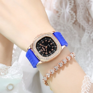 Close-up of rose gold rhinestone square watch with a blue silicone strap on a female wrist