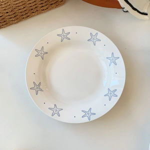 Detailed top view of a white ceramic plate with blue starfish patterns and sea theme