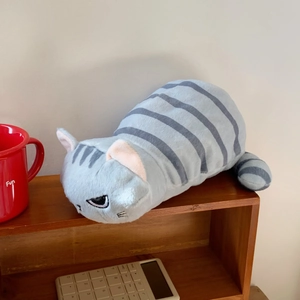 Dettaglio dell'astuccio per gatti in peluche a righe grigie su uno scaffale in legno