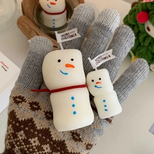 Set of two white snowman scented candles with Merry Christmas flags in a cozy hand setting