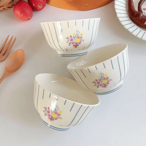 Close-up of ceramic bowls featuring blue vertical stripes and floral pattern in a cozy setting