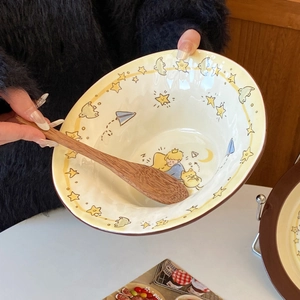 Close-up of ceramic bowl with Little Prince illustrations and a wooden spoon