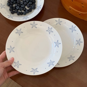 Close-up of white ceramic plate set with blue starfish patterns and dot details