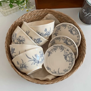 French vintage ceramic dinnerware set with blue floral bird patterns in a woven basket