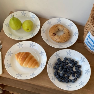 Detail of white ceramic dinner plate featuring blue starfish patterns and fresh fruit