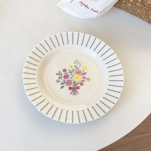 Close-up of French vintage ceramic plate featuring blue stripes and floral bouquet