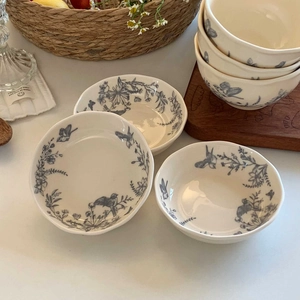 Detail of vintage French ceramic bowls featuring floral and bird patterns on a cream glaze