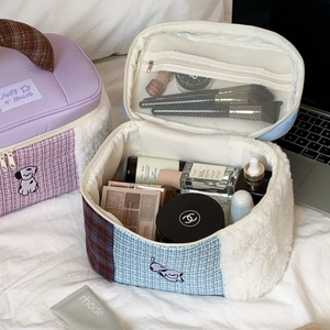 Detail view of large quilted makeup bags with top handles on a cozy bed background