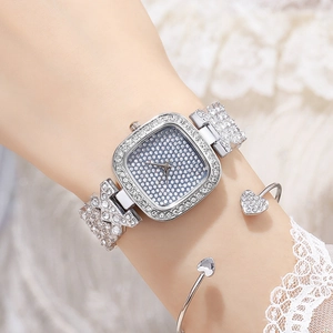 Detailed view of an elegant square silver rhinestone watch worn on a wrist with bangle