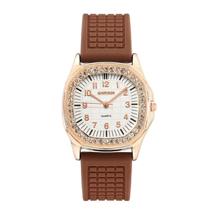 Detail of rose gold square case with crystal bezel and brown textured silicone strap