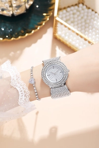 Detailed view of luxury silver rhinestone watch and heart charm bracelet on wrist