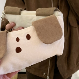 Macro detail of canvas puppy pencil case featuring 3D ears and durable metal zipper