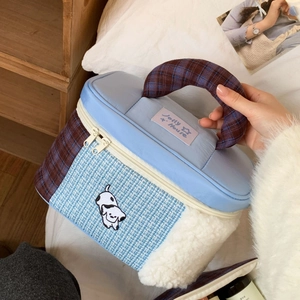Detail of multi-material patchwork makeup bag with plush fleece and cartoon embroidery