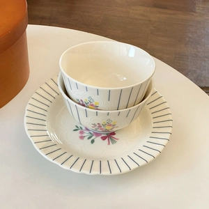 Detailed view of floral ceramic bowls and plate with blue stripes and pink bows